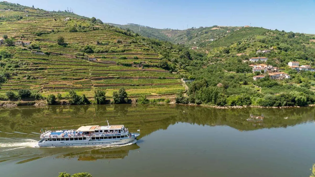 Douro River cruise boat passing terraced vineyards on a Douro River cruise with lunch from Porto, Portugal