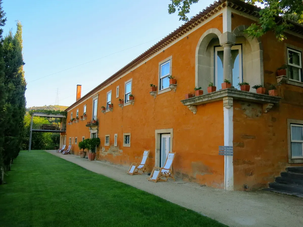 Orange-walled quinta house with a lawn in the Alto Douro wine country on a Douro Valley wine tour from Porto